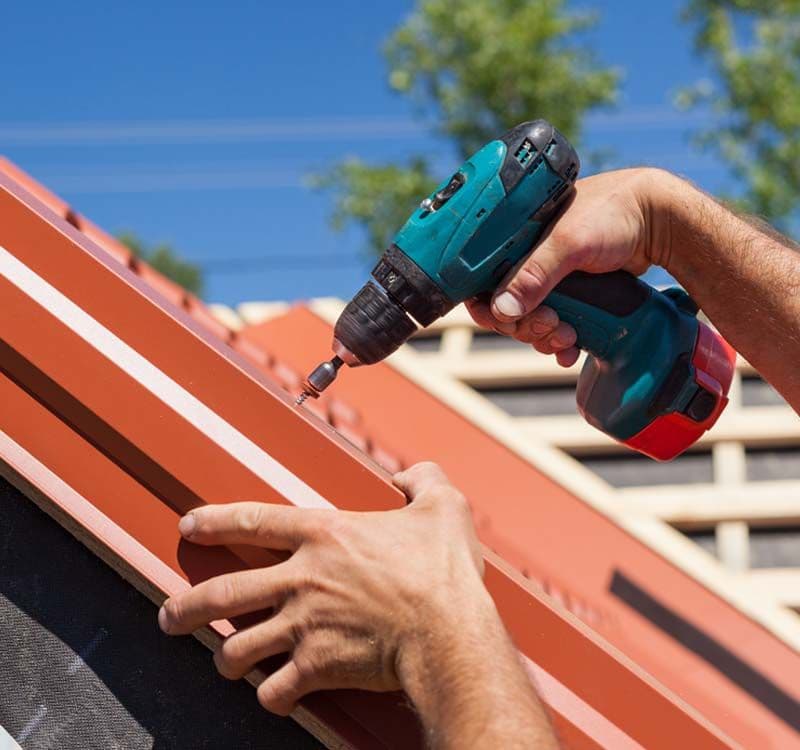 Worker Repairing Roof with Dril